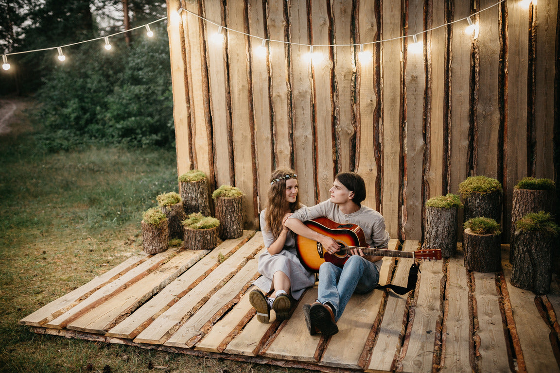 Mark and Aksana, who are MIA - the authors of ceramic shelves and hooks, sit with a guitar on wooden boards on the street. This is the photo zone at our wedding, where we ran barefoot on the grass and sang songs with friends and loved ones! It is our wedding photos that adorn our product photos! All photos of mushroom shelves and hooks have a photo of our wedding day!