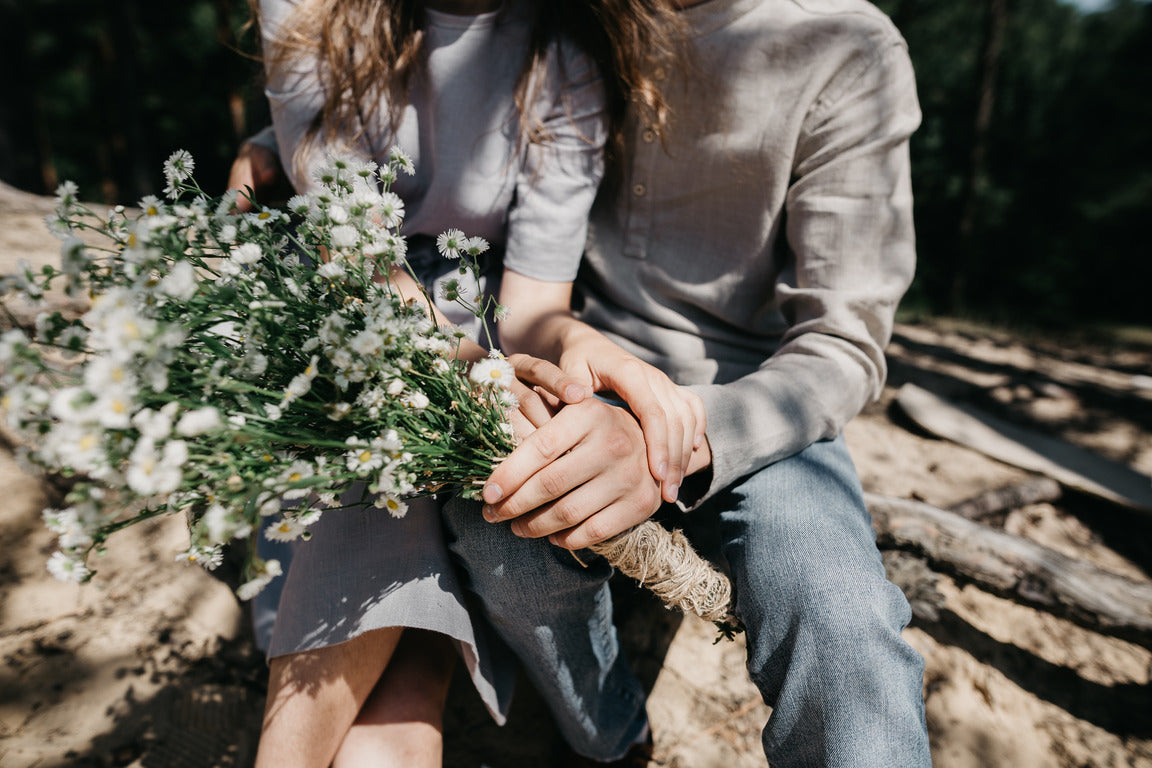 The hands of Mark and Aksana, who work under the pseudonym MIA, hold a bouquet of field daisies. This is a bridal bouquet and there is a photo of this bouquet in many of our photos of mushroom shelves and hooks.